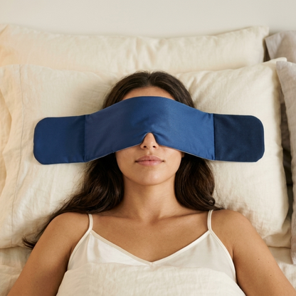 Woman resting on a pillow wearing the navy SomniGrave Weighted Sleep Mask.